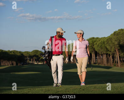 junges Paar zu Fuß zum nächsten Loch am Golfplatz. Mann Golf Tragetasche Stockfoto