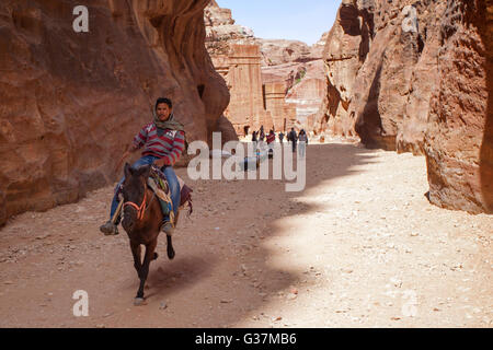 Eine junge Beduine, die auf einem Esel in Petra reitet, auch bekannt als die „Rosenstadt“, Jordanien, Naher Osten. Stockfoto