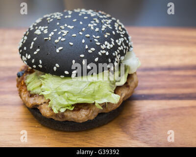 Schwarz-Burger mit Spicy Sauce auf Tablett aus Holz Stockfoto