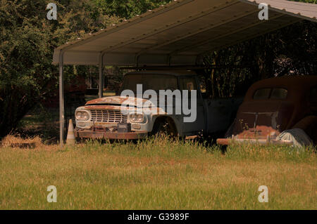 Rostigen LKW neben Oldtimer in einem bewachsenen Feld Stockfoto