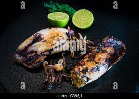 Gebratener Tintenfisch, gefüllt mit Reis auf schwarzem Teller Stockfoto
