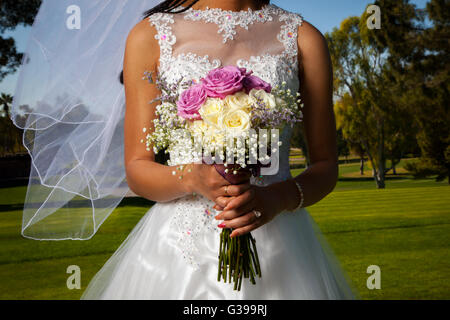 Detail-Bild von einem afroamerikanischen Braut hält ihre rose Bouquet vor ihr.  Ihr Schleier weht sanft im Wind. Stockfoto