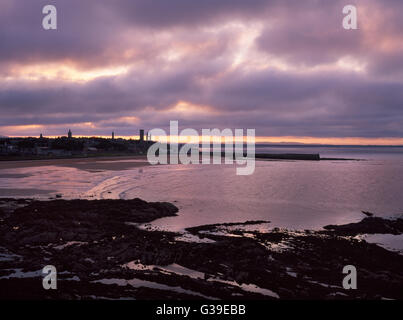 St Andrews, Fife: East Sands & Stadt mit W & E Enden der zerstörten Kathedrale & St Rule Turm aussehende NW von der Klippe nach Sonnenuntergang. Stockfoto