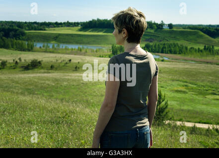 einsame Frau stand mit dem Rücken auf der grünen Wiese Stockfoto