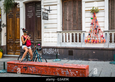 Eine junge Dame mit ihrem Fahrrad überprüft ihr Handy in Montevideo, Uruguay, Südamerika. Stockfoto