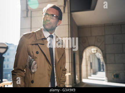 Corporate Geschäftsmann im Trenchcoat stehen im sonnigen Kreuzgang Stockfoto