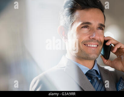 Schließen Sie sich lächelnd corporate Geschäftsmann reden über Handy Stockfoto