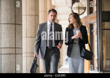 Corporate Geschäftsmann und Geschäftsfrau mit Kaffee gehen und sprechen im Kreuzgang Stockfoto
