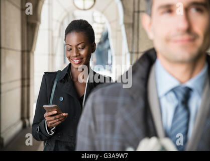 Corporate Geschäftsfrau SMS mit Handy im Kreuzgang Stockfoto