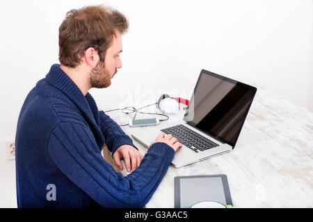 Ein junger Mann mit seinem Laptop zu Hause. Stockfoto