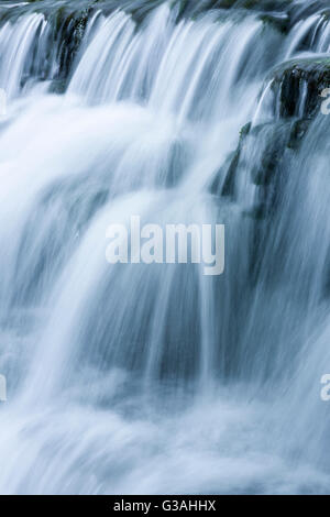 Wasser Kaskadierung über ein Wehr mit Motion blur. Tumbling Wehr auf dem Fluß Yeo in Wrington, North Somerset, England. Stockfoto