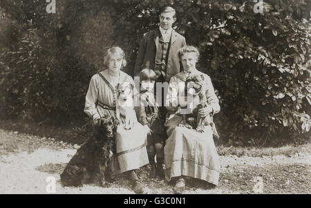 Vier Menschen und drei Hunde in einem Garten Stockfoto