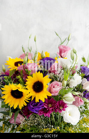 Ein wunderschöner Blumenstrauß mit Sonnenblumen, Rosen und Lisianthus, mit leuchtenden Farben und zartem Grün, Stockfoto