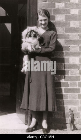 Frau mit Pekingese-Hund vor einem Haus Stockfoto