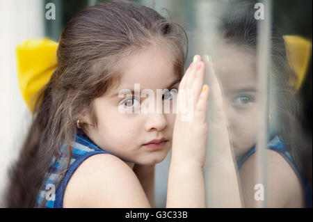 Mädchen stehen gegen Fenster, Hände drückte gegen Glas Stockfoto