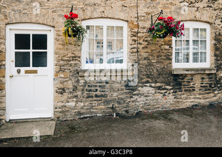 STOW-ON-THE-WOLD, UK-12. August 2015: Limestone Cottage Eingang. Gemalte hölzerne Tür und Fenster mit Blumen geschmückt und Stockfoto