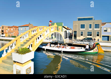 Portugal, Aveiro: Traditionelle Moliceiro Boot vorbei an Canal de Sao Roque unter Kanal-Brücke mit Frau winken für Touristen Stockfoto