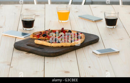 Frische Pizza Getränke und elektronischen Gadgets auf Holztisch Stockfoto