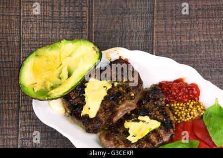 Zwei Gebratene Filet Steaks auf weiße Schale mit Obst Mango, Senf und Tomatenscheiben. Flache Draufsicht. Stockfoto