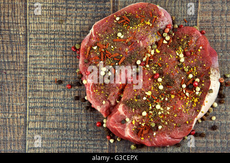 Zwei rohes Rinderfilet Steaks bestreut mit Gewürzen auf hölzernen Hintergrund, flache Ansicht von oben Stockfoto