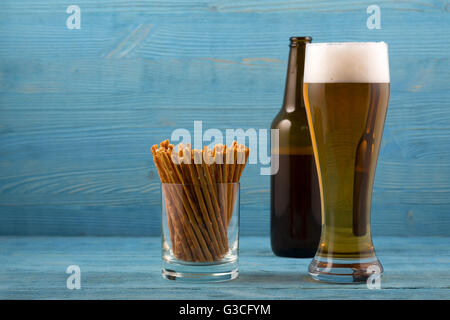 Bier und salzigen Sticks auf blauem Hintergrund Stockfoto