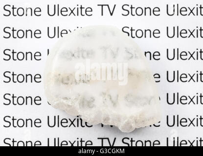 polierte Ulexite (TV Stein) natürlicher mineralischer Edelstein auf Blatt Papier mit Buchstaben. Ulexite bekannt als TV Rock durch Faser-Opt Stockfoto