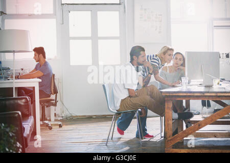 Junge kreative Geschäftsleute arbeiten am Computer in sonnigen Büro Stockfoto