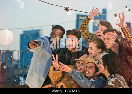 Begeisterte junge Erwachsene Freunde jubeln und nehmen Selfie auf Party auf dem Dach Stockfoto