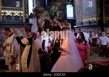 Der ukrainische Bräutigam und die ukrainische Braut werden während der traditionellen Krönungszeremonie einer Hochzeit der östlichen orthodoxen Kirche in der St. Wolodymyr-Kathedrale im Zentrum von Kiew oder Kiew-Ukraine gekrönt Stockfoto