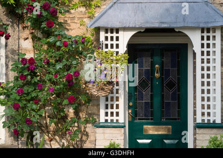 Rote Rosen auf der Vorderseite eines Steinhauses. Bampton, Oxfordshire, England Stockfoto