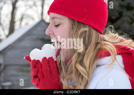 Teenager-Mädchen lecken Eis Herz in rote Handschuhe. Stockfoto