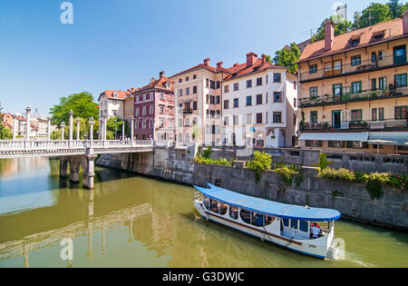 Ljubljana, Slowenien - 7. Juni 2016 Boot am Fluss Ljubljanica und Schuster Brücke im Hintergrund Stockfoto