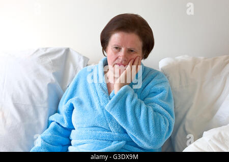Ältere Frau im Bett mit Zahnschmerzen Stockfoto
