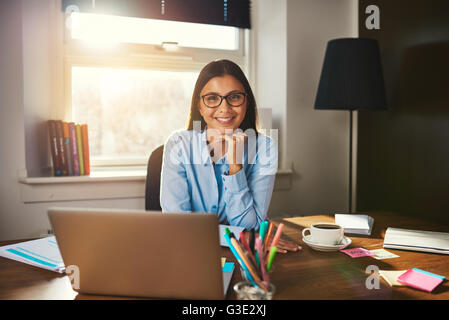 Unternehmerin am Schreibtisch lächelt in die Kamera Stockfoto