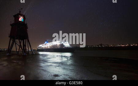 Leichte streaming von einem Leuchtturm an der Küste als ein beleuchteter Kreuzfahrtschiff vergeht; South Shields, Tyne and Wear, England Stockfoto