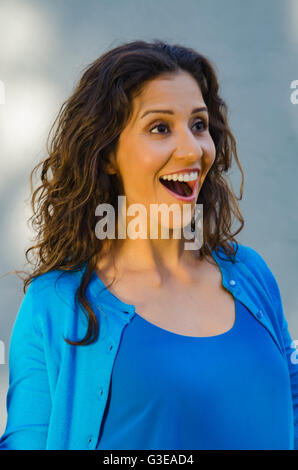 Porträt einer schönen überrascht lachend Hispanic Frau in blauem Hemd und Pullover Stockfoto