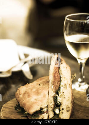 Getönten kreative Bild eines geräucherten Lachs Sandwich in Ciabatta-Brot mit einem Glas Weißwein Stockfoto