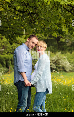 Glückliches Paar im Park, schwangere Frau und ihr Mann Stockfoto