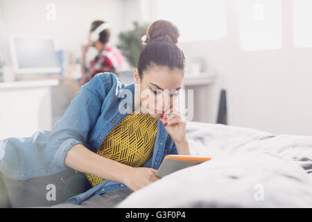 Junge Frau mit digitalen Tablet auf dem Bett Stockfoto