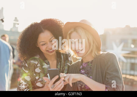 Junge Frauen SMS mit Handy-Party auf dem Dach Stockfoto