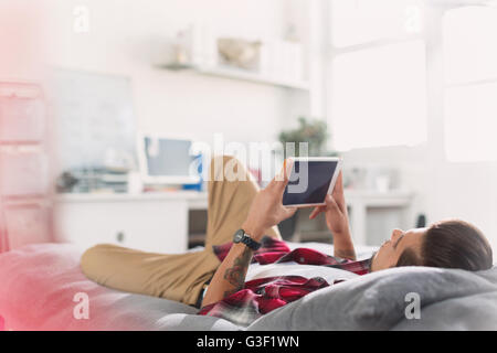 Junger Mann mit digital-Tablette auf Bett Stockfoto