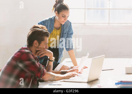 Kreative junge Geschäftsleute arbeiten am Laptop im sonnigen Büro Stockfoto