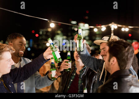 Junge Männer Bier trinken und tanzen auf Party auf dem Dach Stockfoto
