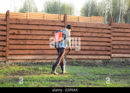 Mann sprüht Rasen mit Herbizid von Ranzen sprayer Stockfoto