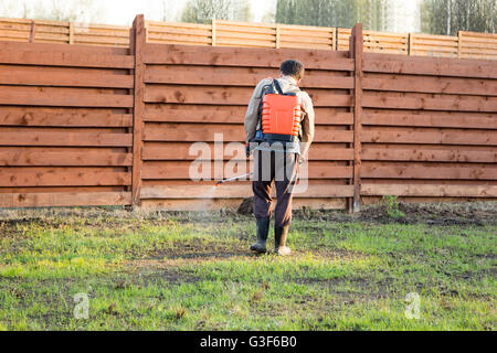 Mann sprüht Rasen mit Herbizid von Ranzen sprayer Stockfoto