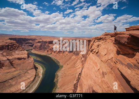 Männliche Wanderer Spaziergänge entlang der Felskante des massiven Horseshoe Bend im nördlichen Arizona. Stockfoto