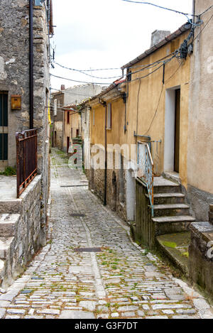 Alte schmale gepflasterte Straße führt zwischen Wohnhäusern in einer italienischen Stadt an einem grauen Himmel-Tag Stockfoto