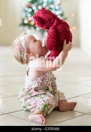 Babymädchen spielen mit roter Teddybär zur Weihnachtszeit Stockfoto