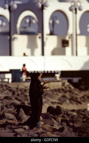 Eine saudische Frau am Strand an der Corniche in der Nähe einer Moschee in Jeddah. Stockfoto