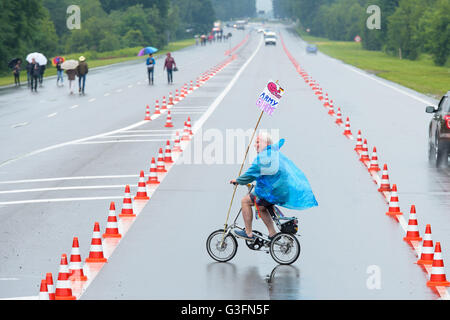 Ramstein-Miesenbach, Deutschland. 11. Juni 2016. Eine Friedensaktivistin, mit dem Fahrrad entlang der Straße gegenüber dem US-Luftwaffenstützpunkt während der "Stopp-Ramstein" Kampagne in Ramstein-Miesenbach, Deutschland, 11. Juni 2016. Sie demonstrieren gegen die US-amerikanischen Luftwaffenstützpunkt und seine Rolle in den Drohnenkrieg. Foto: OLIVER DIETZE/Dpa/Alamy Live News Stockfoto